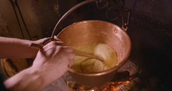 Polenta, traditional cornmeal of Northern Italy. Professional cook preparing food in restaurant kitchen. Man at work as chef and cooking