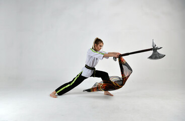 Fototapeta premium beautiful girl in a white-black suit does exercises with a battle ax and a scarf