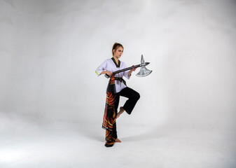 Fototapeta premium beautiful girl in a white-black suit does exercises with a battle ax and a scarf