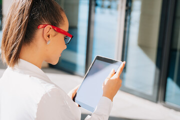 A girl businessman wearing glasses looks at the screen of her electronic tablet, the kind of shady woman who reads a letter online