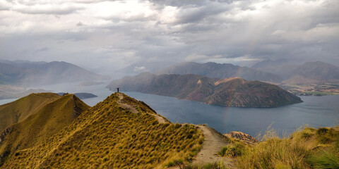 Woman standing on top of a mountain, view of lakes. Roy's Peak, Wanaka, New Zeland