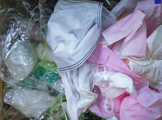Used sanitary napkins, surgical face mask, and plastic in the trash. Medical waste management concept. Waste separation. Unhygienic garbage trash. Disgusting trash bin with dirty medical waste.