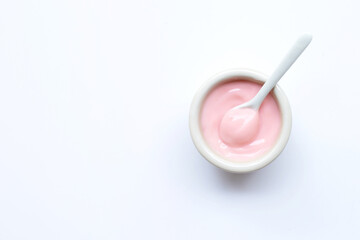 Ceramic bowl of  pink strawberry yogurt on white