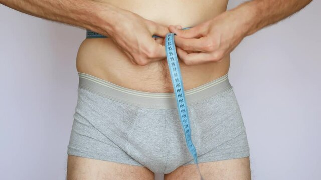 One little fat man measures his waist against white background