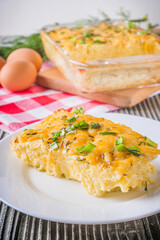Delicious potato casserole with egg and cheese on a gray wooden background