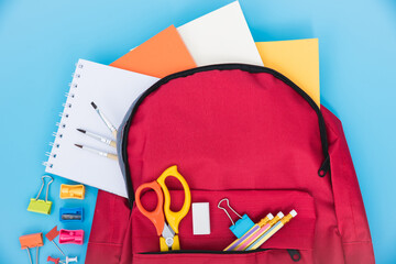 Top view flat lay of red school bag backpack and accessories tools for children education on blue...