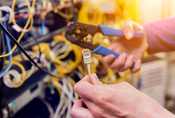 Network engineer working in server room. Connecting network cables to switches