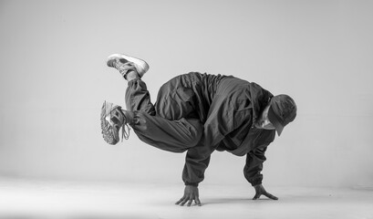A man hip hop dancer or bboy freezes in one pose on a white background. Bboy doing stylish stunts.