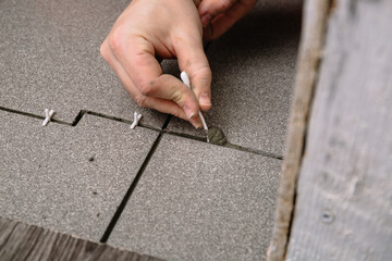 The tiler places new gray tiles on the floor, inserts spacers and carefully processes the seams....