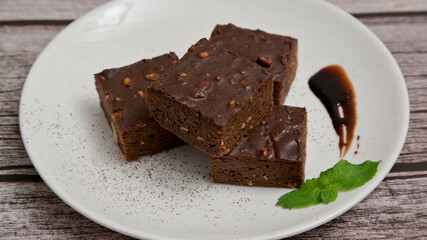 Chocolate brownies nuts in white plate on wooden table. Close up