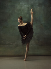 Balanced. Graceful classic ballerina dancing, posing isolated on dark studio background. Elegance...
