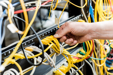Network engineer working in server room. Connecting network cables to switches