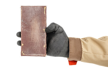 Wooden bar with used sandpaper on top in woodworker hand in black protective glove and brown uniform isolated on white background