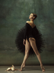 Confident. Graceful classic ballerina dancing, posing isolated on dark studio background. Elegance...