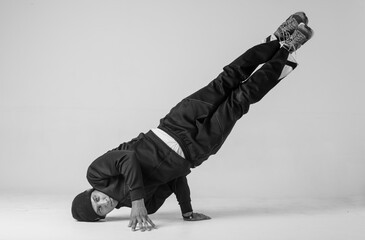 A man hip hop dancer or bboy freezes in one pose on a white background. Bboy doing stylish stunts.