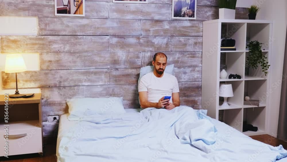 Aufkleber man scrolling on social media using smartphone before going to sleep.