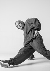 A man hip hop dancer or bboy freezes in one pose on a white background. Bboy doing stylish stunts.