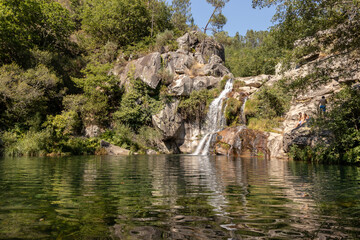 Beautiful and large waterfall that forms a beautiful pool of deep and crystalline waters , Manhouce , Viseu , Portugal - obrazy, fototapety, plakaty