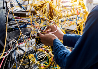 Network engineer working in server room. Connecting network cables to switches