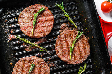 Beef burger patties sizzling on a hot barbecue pan. White background. Top view