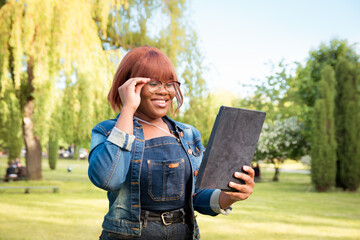 Black student girl communicate using modern means of communication. Portrait of a woman with a tablet in her hands outdoors
