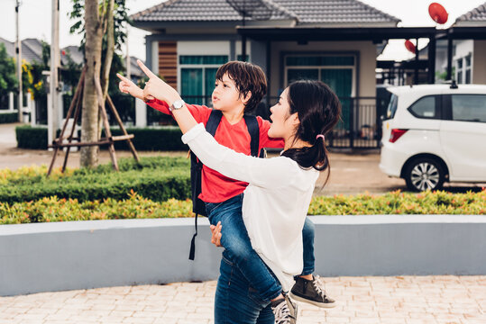 Asian happy mother carrying her kid son family, the kid point hand out with finger outdoors park, Family activity life concept