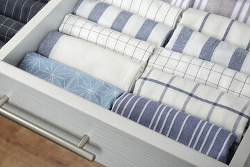 Open drawer with folded towels, closeup. Order in kitchen
