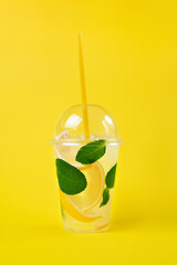 Lemonade to go cup with mint and lemon on yellow background, isolated