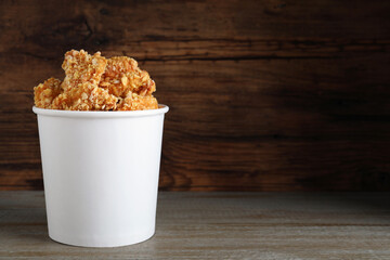 Bucket with yummy nuggets on table against wooden background, space for text