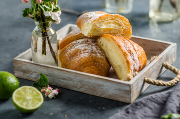 Fresh croissants with lemonade for breakfast. Spring flowers on the table.