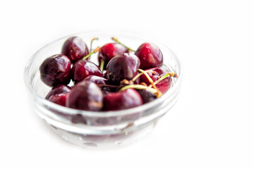 Fresh cherry fruits in glass bowl isolated on white background. Antioxidant, natural, vitamin, organic, vegetarian food berry. Drops of water on surface of berries. Selective focus. Macro background
