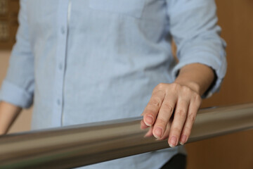 Woman leaning on metal railing indoors, closeup