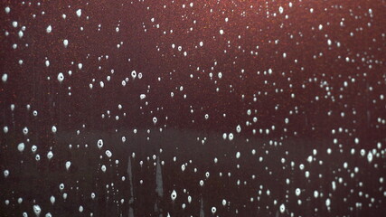 The applied foam on the car to remove dirt flows down closeup. Special detergent for car wash. © Vital9c