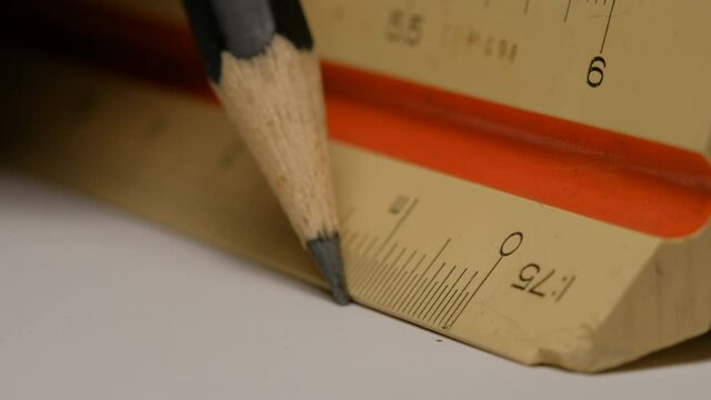 Close up of using a triangular scale ruler with pencil on white paper draw architectural drawings, models. Scale 1:75.