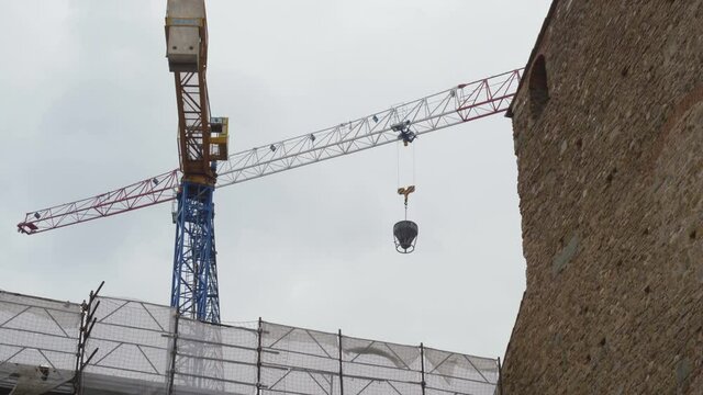 A medieval church in Florence while tower cranes are moving in the sky