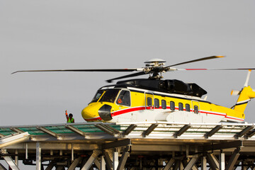 A helicopter on top of a offshore oil-platform transporting roughnecks 