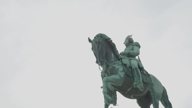 Handheld track shot of Karl Johan statue in front of Royal Palace building on overcast day, in Oslo Norway