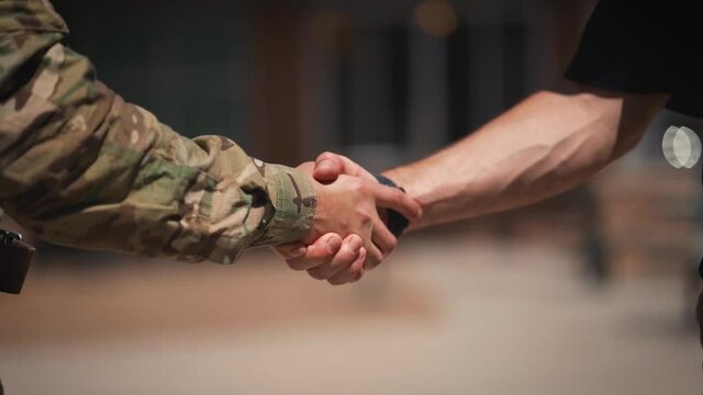 Soldier and civilian arms shaking hands close up slow motion