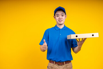 Asian delivery man holding pizza or parcel box over yellow isolate background. Work from home and delivery concept.