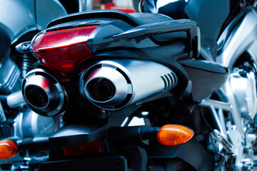 Exhaust pipes and brake light of a motorcycle closeup. The noise of a sports bike in a garage. Rear...