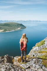Naklejka premium Travel in Norway woman traveler with backpack standing on cliff alone outdoor summer vacations adventure lifestyle solo trip aerial sea fjord landscape