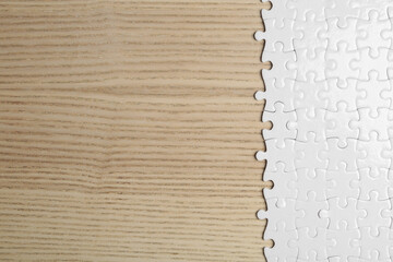Blank white puzzle pieces on wooden background, flat lay. Space for text