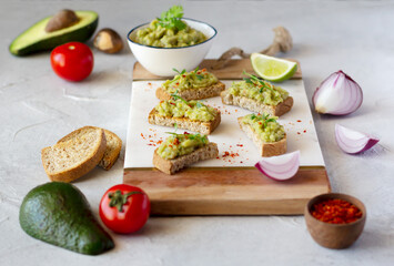 Guacamole toasts on wooden board. Ingredients