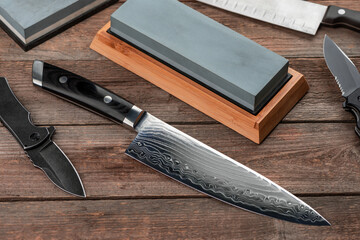 Top view on Japanese chef's and Santoku knives, pocket knives and whetstones