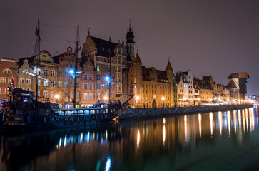 Fototapeta na wymiar Barco en Gdansk, Polonia. Fotografía urbana nocturna de paisaje urbano. Río y edificios.