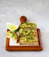 Guacamole toasts on a wooden board. Healthy and tasty snack. Copy space