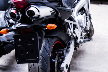 Closeup back of sportbike in garage Wheel, brake disc, exhaust pipe, transmission, shock absorbers, engine, brake lights. Color photo of chrome details of road bike Free space under the license plate