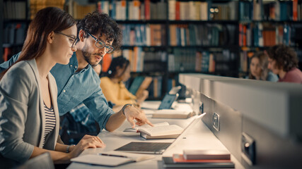 University Library: Talented Caucasian Girl uses Laptop, Smart Helpful Classmate Explains and Advices Her with Class Assignment. Happy Diverse Students Talking, Learning, Studying Together for Exams