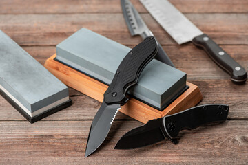 Various knifes and whetstones on wooden background