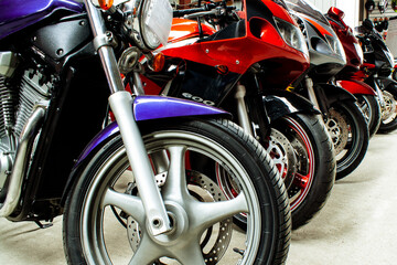 Beautiful group parking of motorcycles in a showroom for sale, in a store close-up. Maintenance of sportbikes, road bikes in the workshop. Moto parts, wheels, headlights, engine.